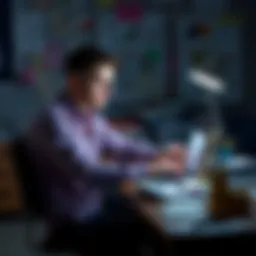 A young man sitting at a desk covered in bills and papers, looking stressed as he calculates his budget on a laptop.